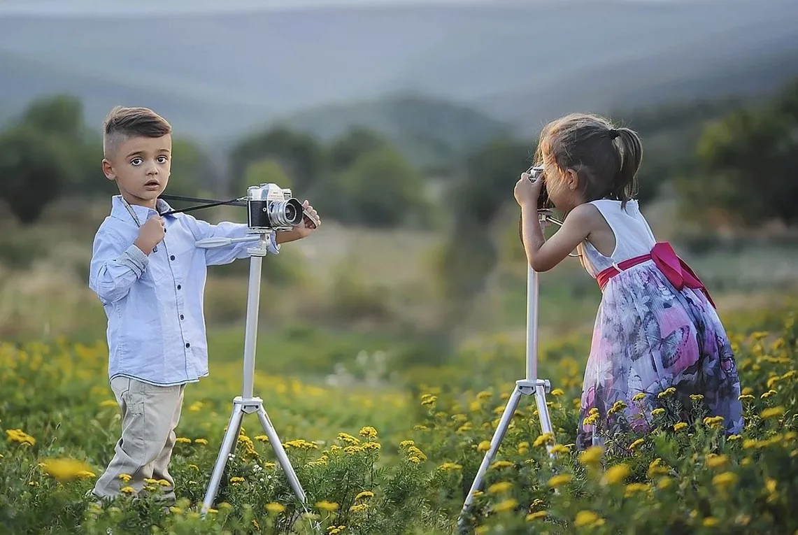 花畑の中で三脚のカメラを構える男の子と女の子